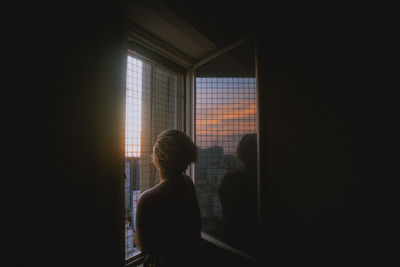 Rear view of woman looking through window