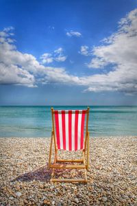Deck chair at beach against sky