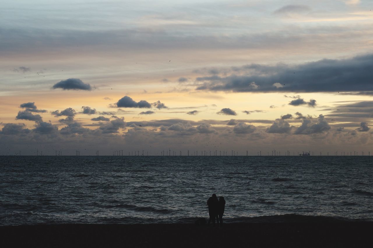 SILHOUETTE MAN STANDING AT BEACH DURING SUNSET