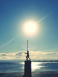 Silhouette lighthouse by sea against sky