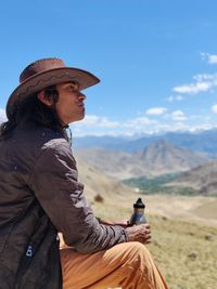 Side view of senior man sitting against sky