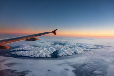 Aerial view of snowcapped mountains against sky during sunset