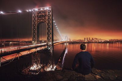 Illuminated bridge over river against sky at night