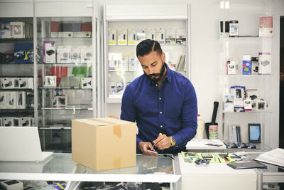 Technician repairing mobile phone at counter in electronics store