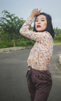 Side view of young woman standing on road