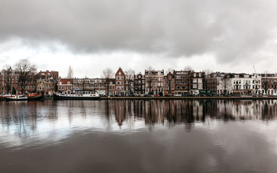 City at waterfront against cloudy sky