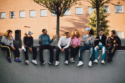 Full length of multi-ethnic friends sitting at skateboard park