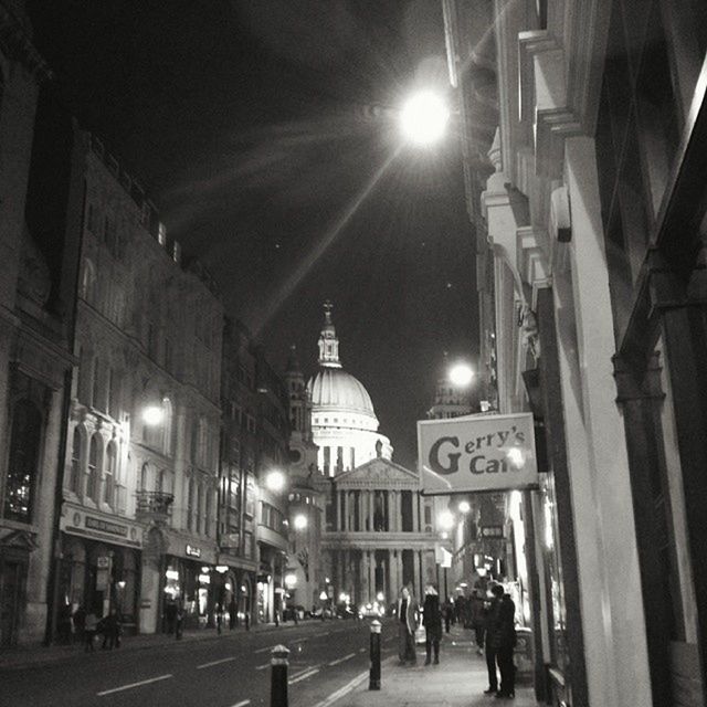 illuminated, architecture, built structure, building exterior, night, city, large group of people, city life, lighting equipment, men, street, street light, walking, lifestyles, person, city street, sky, incidental people, road