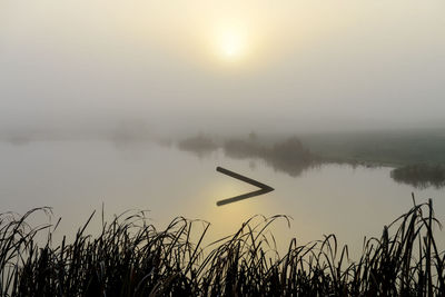 Scenic view of lake against sky during foggy weather