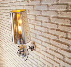 Close-up of illuminated lamp on white brick wall