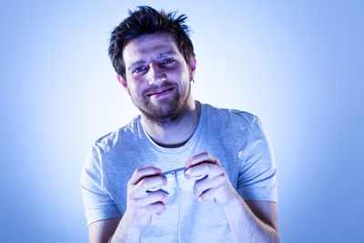 Portrait of mid adult man holding bottle against blue background