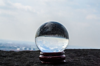 Close-up of crystal ball against sky