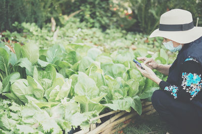 Rear view of young woman standing amidst plants