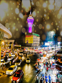 Illuminated street amidst buildings in city at night