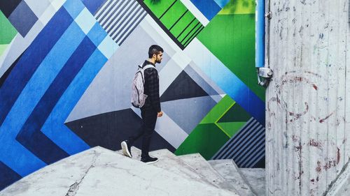 Side view of young man standing against wall