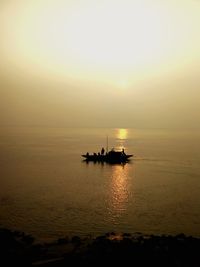 Silhouette boat in sea against sky during sunset