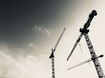 Low angle view of cranes against sky