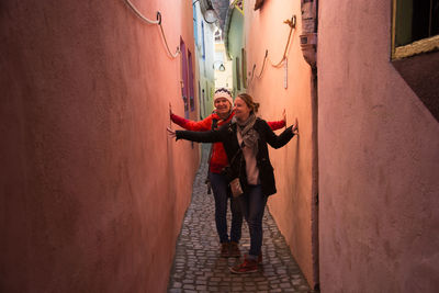 Friends standing in alley amidst wall