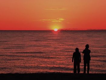 Silhouette people on beach against sky during sunset