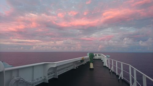 Cruise ship sailing at sea against cloudy sky during sunset