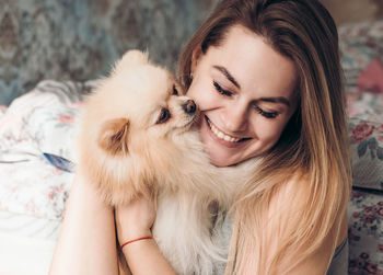 Lovely smiling girl hugging pet dog with passion, eyes closed.