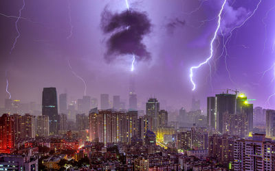 Lightning in sky over city buildings at night