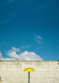 Low angle view of yellow flag against blue sky