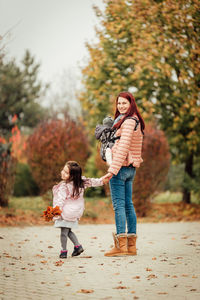 Young mom with two daughters taking a breath of fresh air outdoors after the covid-19 quarantine