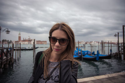 Portrait of smiling woman standing at harbor against sky