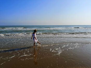 Girl on beach against clear sky