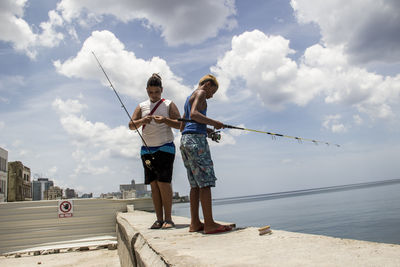 Full length of men standing by sea against sky