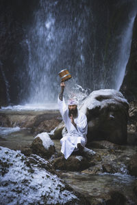 Man standing on rock against waterfall