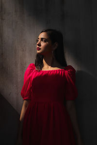 Young woman standing against wall