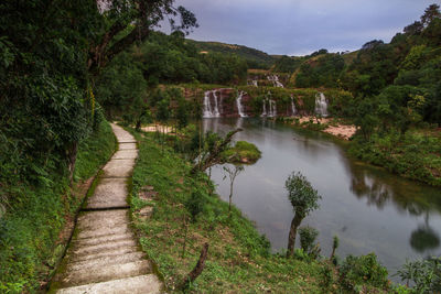 Scenic view of waterfall amidst trees against sky