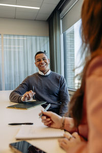 Happy businessman discussing with female colleague in coworking office