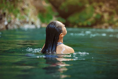 Young latina woman swimming in rio fortuna in costa rica with totally wet long hair