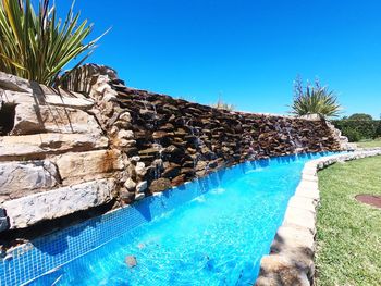 Swimming pool by sea against clear blue sky