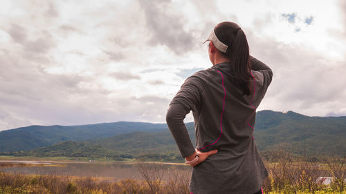 Rear view of woman standing on mountain against sky