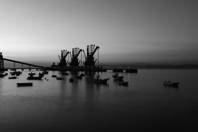 Boats in sea against sky at dusk