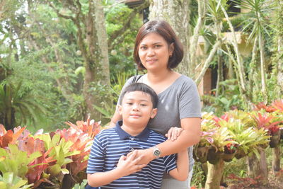 Portrait of mother and son standing against plants