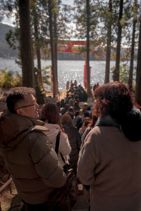 Rear view of people standing against trees during winter