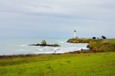 Lighthouse by sea against sky