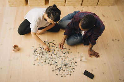 High angle view of couple playing puzzle in living room at home