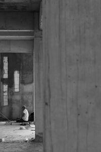 Man sitting on wall of building