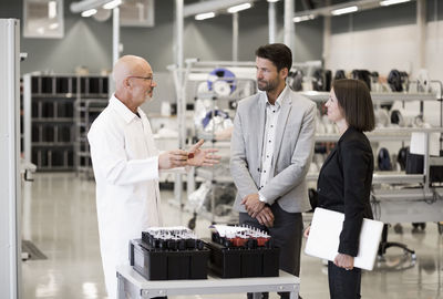 Male engineer and business people discussing in machine industry