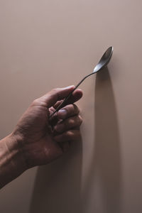 Close-up of hand holding cigarette against gray background