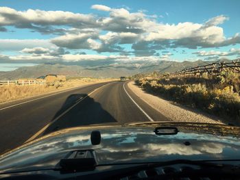 Cars on road against sky seen through car windshield