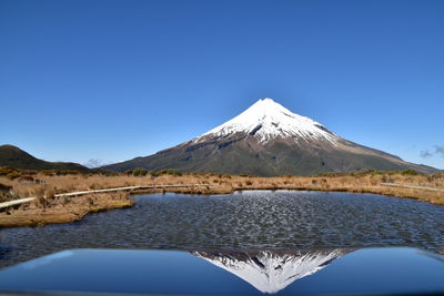 Reflection of snowcapped mountain in lake against blue sky