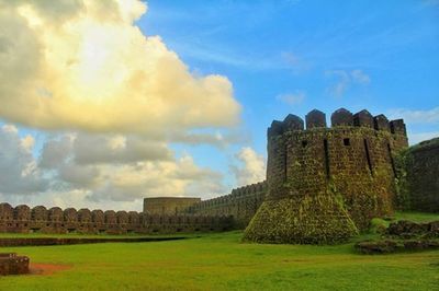 Castle on grassy field against blue sky