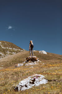 Young woman hiking in the mountains standing on a rocky summit ridge with backpack.lifestyle concept